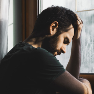 Man depressed looking out a rainy window